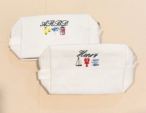 Two white pouches with embroidered designs and text on a beige background