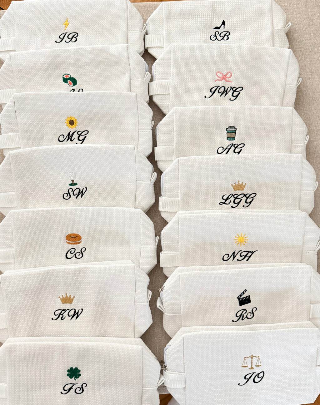 Set of white pouches with various monograms and symbols on a beige background