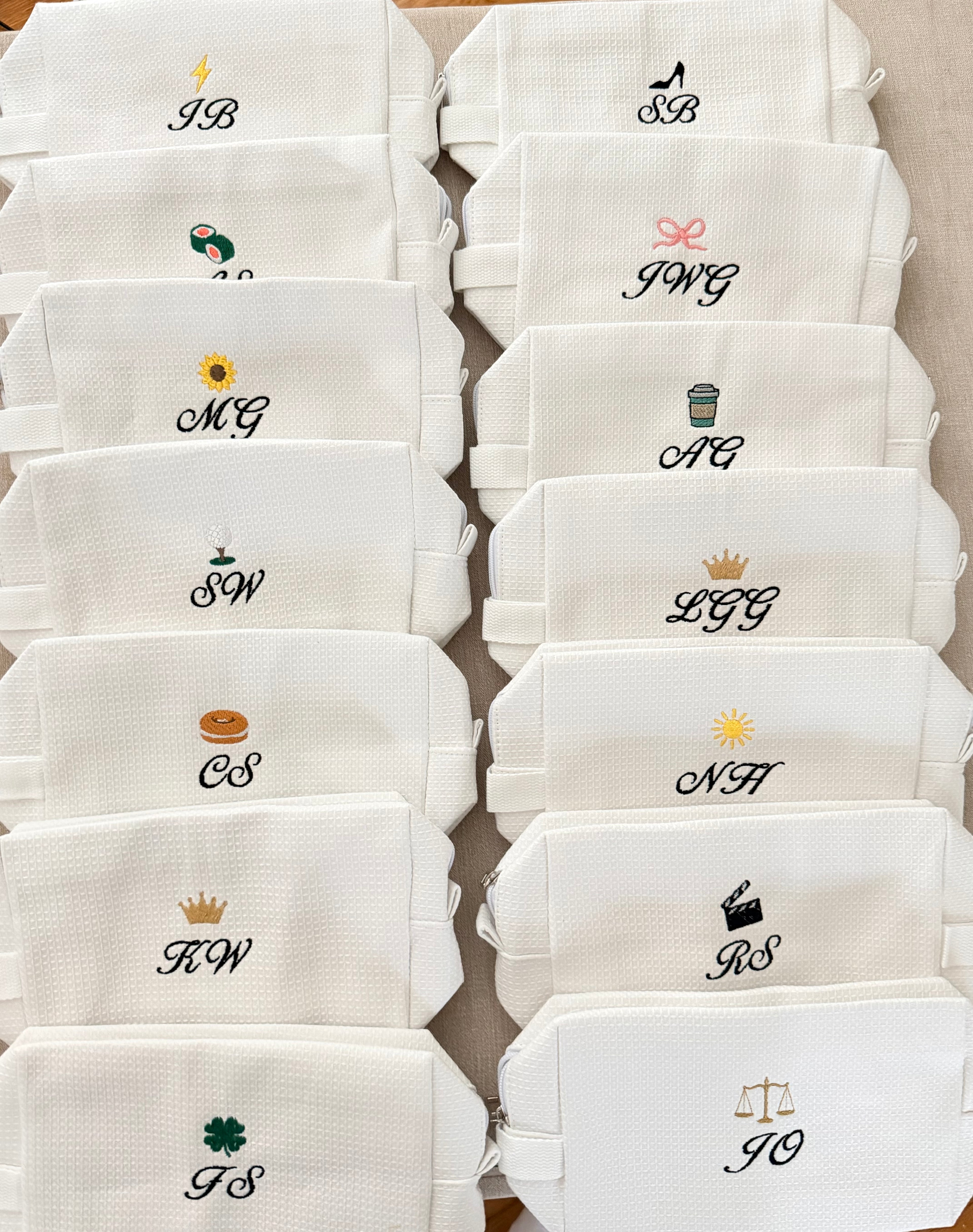 Set of white pouches with various monograms and symbols on a beige background