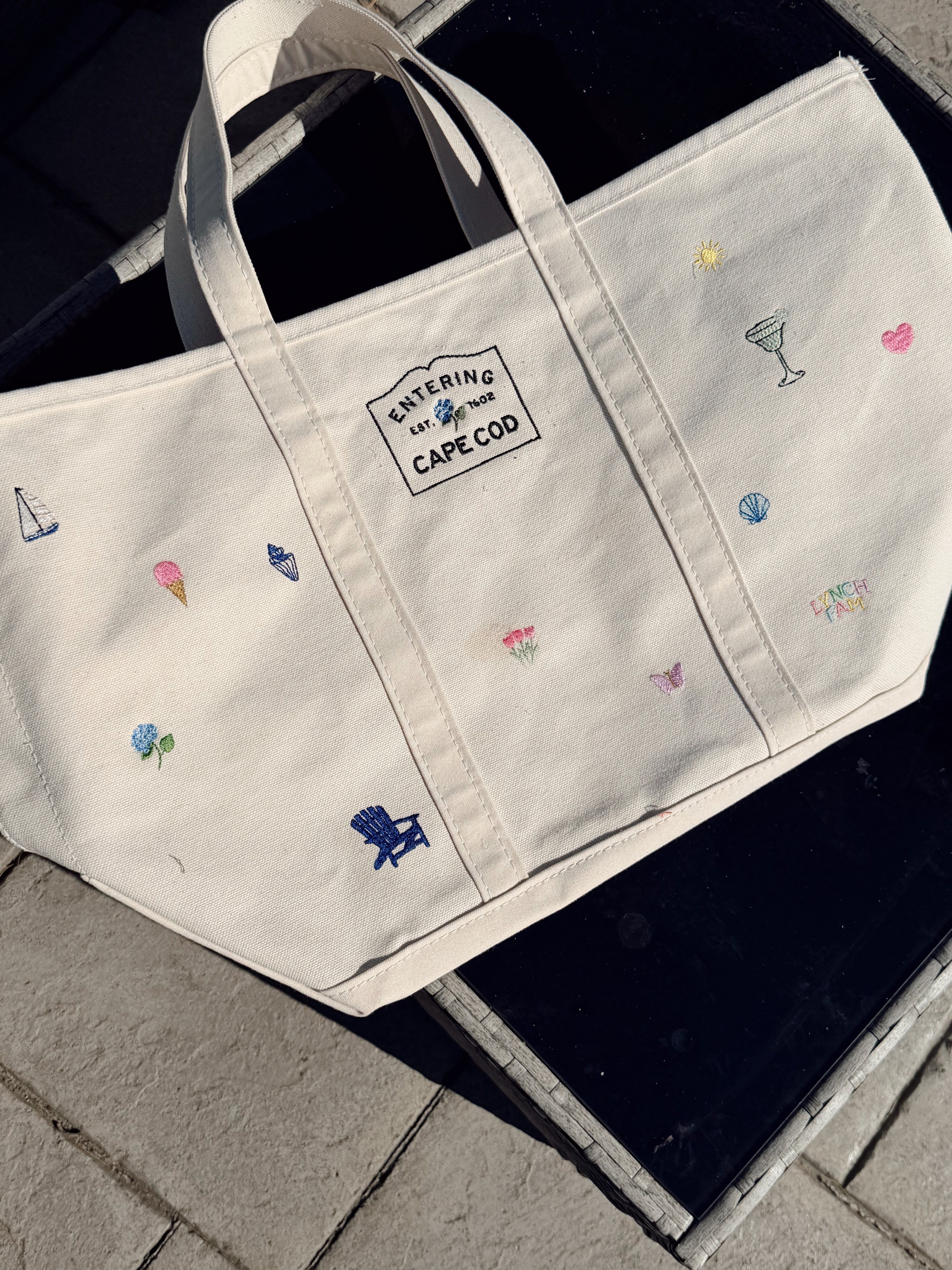 Beige embroidered tote bag with custom icons on black surface